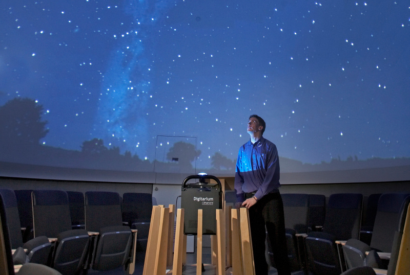 Inside the planetarium View of inside the planetarium with a person standing at a podium in front of a field of stars